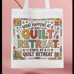 May include: White tote bag with the text "WHAT HAPPENS AT A QUILT RETREAT STAYS AT A QUILT RETREAT" in colorful letters. The design includes images of sewing tools and quilt block patterns.