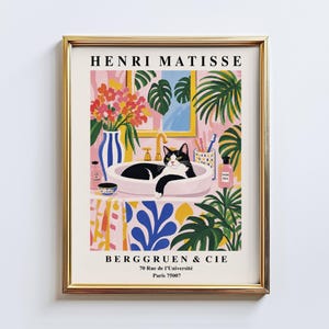 Pode incluir: Uma impressão de arte emoldurada de Henri Matisse Berggruen & Cie apresentando um gato preto e branco descansando em uma pia. A ilustração inclui um vaso listrado de azul e branco com flores, folhas de monstera verdes e acessórios rosa.