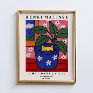 May include: Framed art print featuring a whimsical illustration of a yellow cat peeking out of a blue flower pot. The artwork, titled "Chat Dans Le Pot" by Henri Matisse, includes a pink floral background and a red tiled floor.