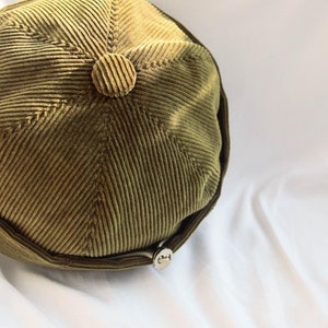May include: A green corduroy bucket hat with a small button on top.