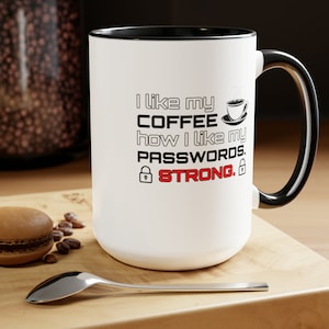 May include: White coffee mug with a black rim and handle. The mug has a black and white graphic that says "I like my coffee how I like my passwords. STRONG." with a lock symbol on either side of the word STRONG.