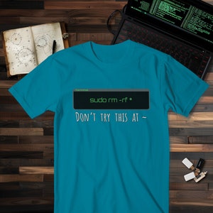 May include: A turquoise blue t-shirt with a black and green graphic of a computer terminal window displaying the text "sudo rm -rf *" and the text "DON'T TRY THIS AT ~" underneath.