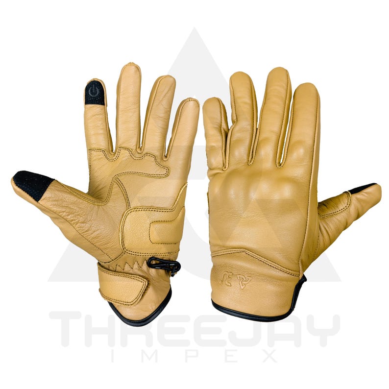 Peut inclure: Paire de gants en cuir beige avec des d&eacute;tails noirs sur les bouts des doigts et les poignets. Les gants pr&eacute;sentent des coutures renforc&eacute;es et une sangle de poignet. La marque "THREEJAY IMPEX" est imprim&eacute;e en bas.