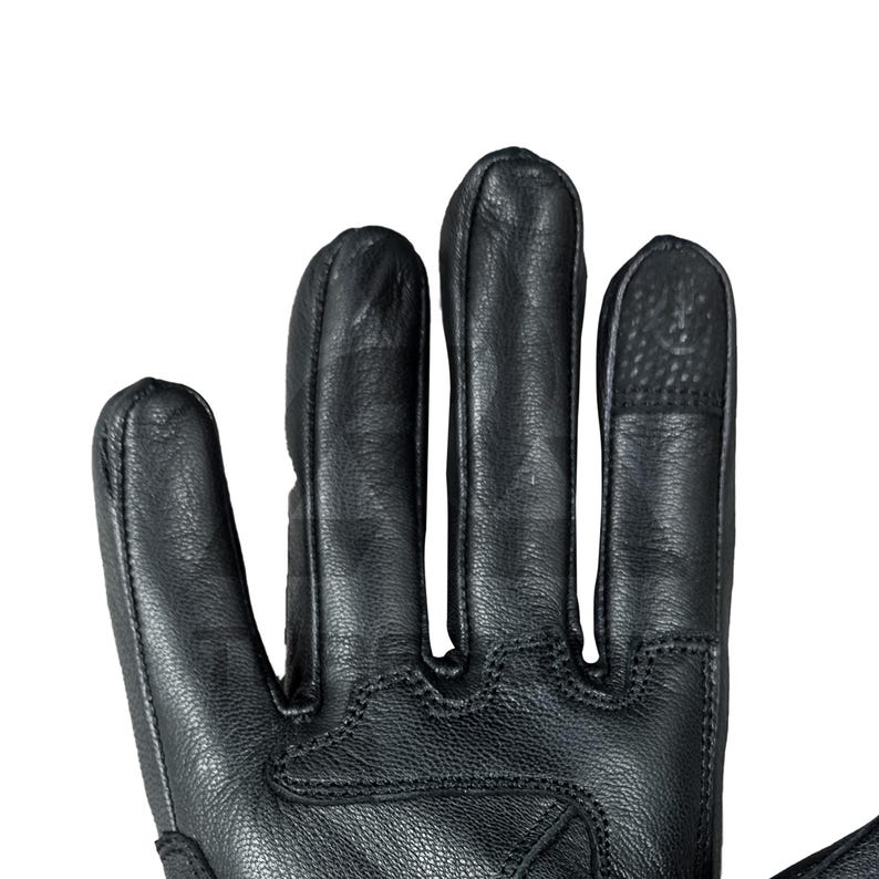 Peut inclure: Gros plan d'un gant en cuir noir. Le gant pr&eacute;sente des coutures d&eacute;taill&eacute;es et un bout de doigt textur&eacute; sur un doigt. Le cuir semble souple et le design sugg&egrave;re durabilit&eacute; et protection.