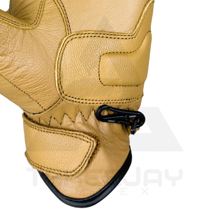 Peut inclure: Gros plan sur un gant de travail en cuir beige avec des d&eacute;tails noirs. Le gant pr&eacute;sente des coutures renforc&eacute;es, une sangle de poignet et un mousqueton noir. Le design sugg&egrave;re durabilit&eacute; et protection.