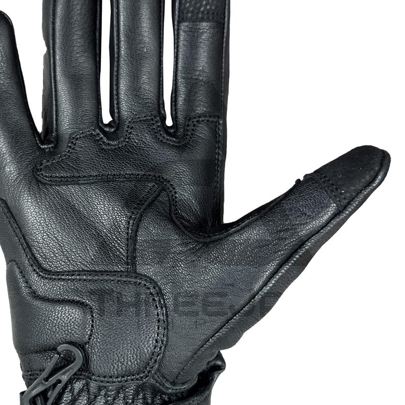 Peut inclure: Gros plan d'un gant en cuir noir, avec des coutures d&eacute;taill&eacute;es et des panneaux textur&eacute;s. Le gant est dot&eacute; d'une fermeture de poignet s&eacute;curis&eacute;e et de zones renforc&eacute;es pour la protection. Le design sugg&egrave;re durabilit&eacute; et adh&eacute;rence.