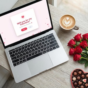 May include: A laptop screen shows a Valentine's Day message: "Will you be my Valentine?" with "Yes" and "No" options. A coffee cup with latte art, a bouquet of red roses, and a heart-shaped chocolate box are on a wooden table.