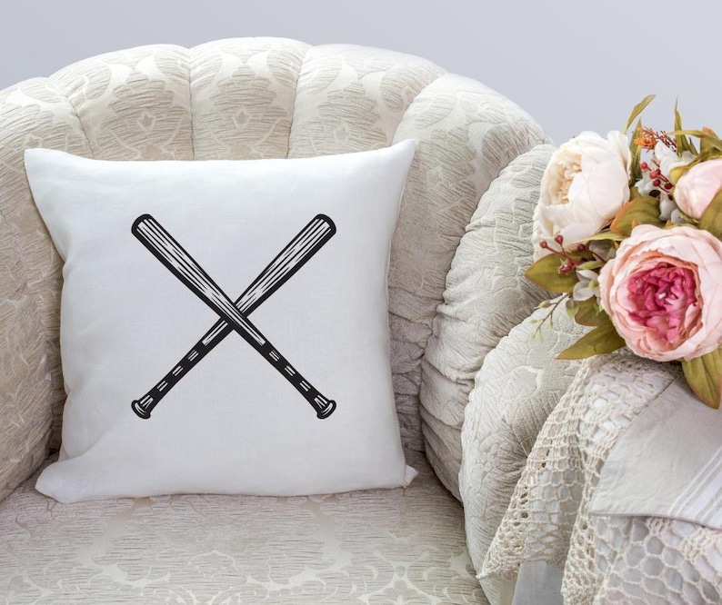May include: White throw pillow with a black graphic of two baseball bats crossed over each other.