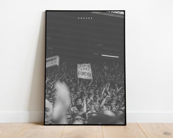 May include: Black and white photo of a crowd of people at a concert, holding up their hands in the air. A sign in the crowd reads "Jurgen Lives Forever".