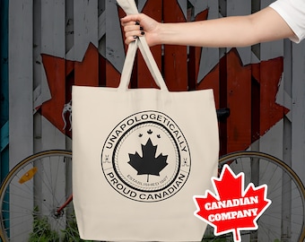 May include: A white canvas tote bag with black text and a black maple leaf design. The text reads "Unapologetically Proud Canadian" and "Established 1867". A red maple leaf sticker with the text "Canadian Company" is in the lower right corner of the image.