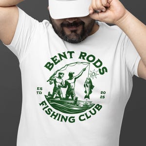 May include: A white t-shirt with a green circle logo that says "Bent Rods Fishing Club" with two men fishing in a boat and a fish on a line. The text "Est'd 2025" is also on the logo.
