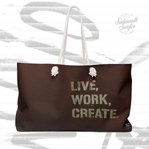 Könnte beinhalten: Eine braune Tragetasche mit weißen Seilgriffen und goldenen Akzenten. Die Tasche hat den Text "LIVE, WORK, CREATE" in einer verwitterten Schrift auf der Vorderseite aufgedruckt.