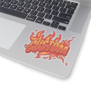 May include: A sticker with the word "CUSTOM" in a bold, red font with a yellow outline. The word is surrounded by flames in shades of orange and yellow.