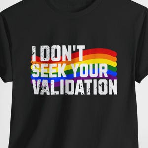 Può includere: Maglietta nera con un design a strisce arcobaleno e il testo "I don't seek your validation" in bianco.