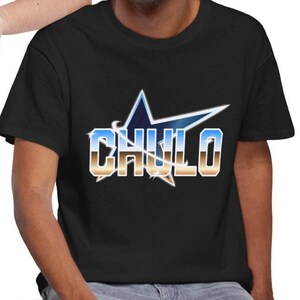 May include: Black t-shirt featuring the word "CHULO" in a stylized font, set against a blue and gold star design. The shirt has a crew neck and short sleeves. The text is outlined in white.