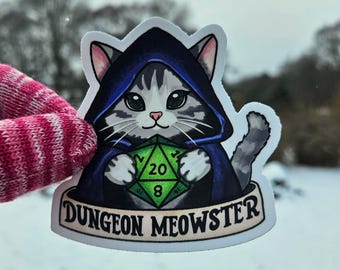 Può includere: Un adesivo raffigurante un gatto dei cartoni animati con un mantello blu con cappuccio, che tiene in mano un dado D20 verde. L'adesivo riporta la scritta "DUNGEON MEOWSTER" su uno stendardo. Il gatto è grigio e bianco con dettagli rosa.