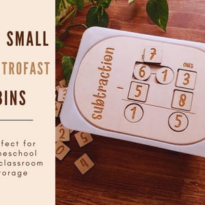 May include: A wooden subtraction learning toy with a white border. The toy has cutouts for number tiles and the word "subtraction" is printed on the side. The image also shows loose number tiles and the text "FITS SMALL IKEA TROFAST BINS".
