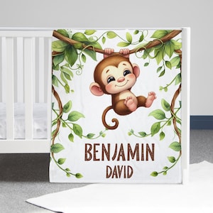 May include: A white baby blanket with a cute cartoon monkey hanging from a vine. The blanket has green leaves and the text "BENJAMIN DAVID" printed on it.