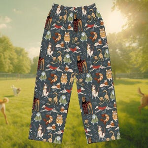 Könnte beinhalten: Graue Schlafanzughose mit einem sich wiederholenden Muster verschiedener Hunderassen, Knochen und Tennisbällen. Die Hunde sind in verschiedenen Outfits und Posen dargestellt. Die Hose besteht aus einem weichen, bequemen Material.