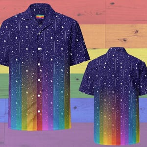 May include: A short-sleeved button-down shirt with a dark blue background and a pattern of white stars and shooting stars. The bottom of the shirt fades into a rainbow gradient. The shirt has a collar and white buttons.