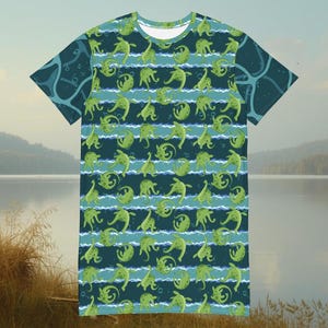 Könnte beinhalten: Kurzärmeliges Kleid mit einem sich wiederholenden Muster aus grünen Meereskreaturen auf einem blau-weiß gestreiften Hintergrund. Das Kleid hat einen runden Ausschnitt und eine lockere Passform. Die Ärmel und der obere Rücken haben ein dunkelblaugrünes Design.