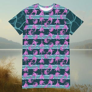 Könnte beinhalten: Kurzärmeliges Kleid mit einem sich wiederholenden Muster aus rosa Meereskreaturen auf einem tealfarbenen Hintergrund mit horizontalen Streifen. Das Kleid hat einen runden Ausschnitt und eine lockere Passform, geeignet für Freizeitkleidung.