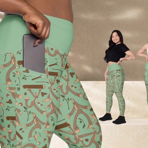 Könnte beinhalten: Grüne Leggings mit einer Tasche an der Seite. Die Leggings haben ein Muster aus braunen Strichmännchen, die auf einem grünen Hintergrund laufen.