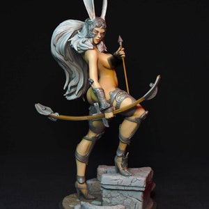 以下が含まれることがあります： 長い白髪、ウサギの耳のヘルメット、装飾的な鎧を着た戦士の女性の精巧な置物。 弓と矢を持ち、石の台座の上に立っています。 このフィギュアはグレーとタンの色合いで塗装されています。