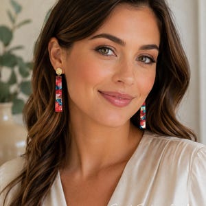 Peut inclure: Boucles d'oreilles pendantes composées d'un clou circulaire doré à la texture martelée et d'un long pendentif rectangulaire. Le pendentif est en résine multicolore avec un motif marbré dans des tons de rouge, de bleu et de blanc.
