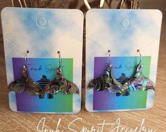 Puede incluir: Dos pares de pendientes de concha de abulón con ganchos de plata, expuestos en tarjetas con un degradado azul, morado y verde. Los pendientes tienen forma de abanico con colores iridiscentes. El texto "Inuk Spirit Jewelry" está escrito en cursiva.