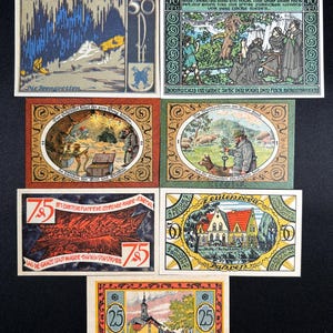 May include: A collection of seven rectangular German Notgeld banknotes featuring various illustrations, including a cave, a religious scene, a treasure chest, a shepherd with a dog, a fire scene, a house, and a town landscape with text in German.