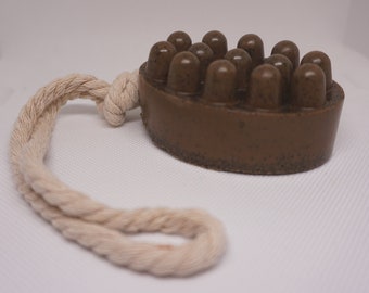 May include: A brown soap bar with a rope handle. The soap has a textured surface with raised bumps.