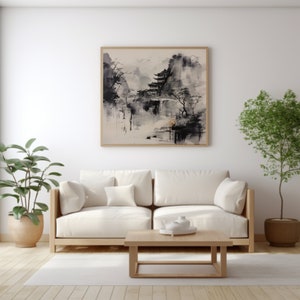 May include: A white couch with two pillows sits in front of a white wall with a framed black and white ink painting of a Japanese landscape. A wooden coffee table sits in front of the couch. A potted plant is on the left side of the couch and another potted plant is on the right side of the couch.