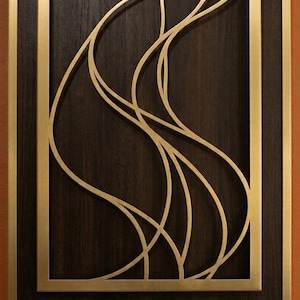 May include: A rectangular wall panel featuring a dark brown wood grain background framed in brushed gold metal. A gold metal cutout overlay with fluid, intersecting curved lines is centered within the frame, creating an abstract pattern.