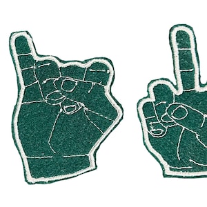 May include: Four green foam hand cutouts spelling the word "LOVE". Each hand has a white outline and detailed stitching. The "L" shows a raised index finger and thumb, the "O" is a raised index finger, the "V" is a peace sign, and the "E" is a fist.
