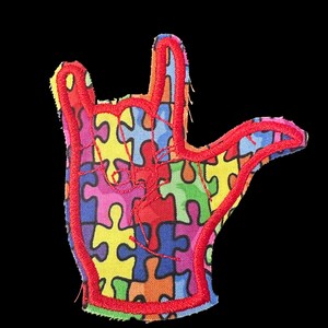 Könnte beinhalten: Gestickter Aufnäher in Form einer Hand, die das "Ich liebe dich"-Zeichen macht. Der Aufnäher hat einen roten Umriss und ist mit bunten Puzzleteilen gefüllt. Der Hintergrund ist schwarz.