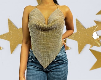 May include: A gold sequined halter top with a cowl neck and a triangular shape. The top is made of a fine mesh material and has a delicate chain strap.