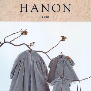 May include: A book titled "HANON" with a Japanese title above it. The cover features three gray dresses hanging on a bare branch. The back cover features a list of contents in Japanese and a logo for "fateless ebooks".