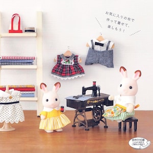 Könnte beinhalten: Ein Buchcover mit dem Titel "Sylvanian Families" und dem Text "Silvanian Family's Dress-Up Book" in Japanisch. Das Cover zeigt Illustrationen einer Nähmaschine, Stoff und einer Hasenpuppe, die ein Kleid trägt.