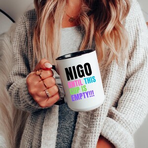 Può includere: Tazza in ceramica bianca con bordo e manico neri. La tazza ha testo nero che recita "NIGO UNTIL THIS CUP IS EMPTY!!" con le parole "UNTIL" e "CUP" in colori arcobaleno.