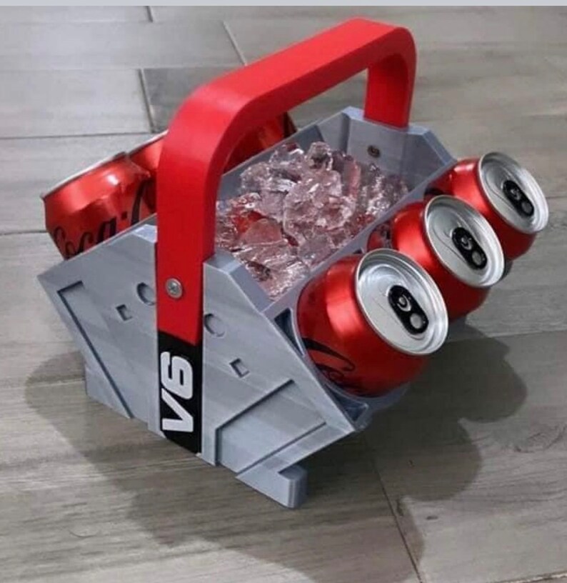 May include: A gray and red six-pack cooler with a handle. The cooler is filled with ice and has four red cans inside. The cooler has the text "V6" printed on the side.