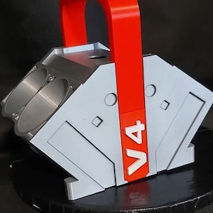 May include: A gray and red 3D printed model of a V4 engine with a red handle. The model has a "V4" label on the side.