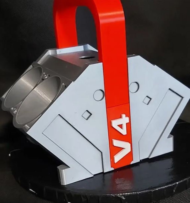 May include: A gray and red 3D printed model of a V4 engine with a red handle. The model has a "V4" label on the side.