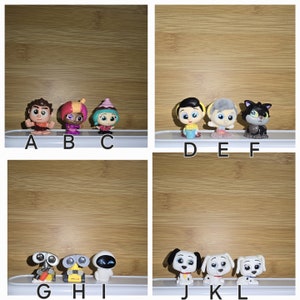 May include: A set of 12 small plastic figurines, including characters from popular animated films. The figurines are arranged in rows on a wooden surface. The characters include a girl with pink hair, a boy with blue hair, a girl with a pink dress, a boy with a blue shirt, a black cat, a white dog, a robot with a blue body, a robot with a red body, and a robot with a silver body.