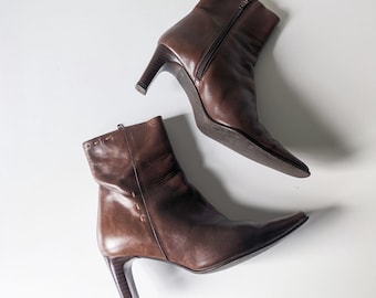 May include: A pair of brown leather ankle boots with a pointed toe and a stiletto heel.