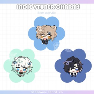 以下が含まれることがあります： インディーVTuberチャーム、各5cmで、3つのユニークなアニメスタイルのキャラクターが特徴です。チャームは、青とミントグリーンの花型の背景に配置されています。「Indie VTuber Charms」の文字が上部に表示されています。