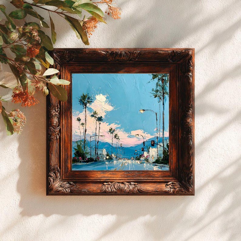 May include: A square oil painting in a dark brown ornate wooden frame depicting a street scene with tall palm trees against a bright blue sky with pink and white clouds. The artwork features thick, textured brushstrokes and a road perspective.