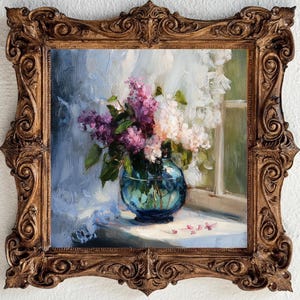 May include: An oil painting in a decorative, ornate, antique-style gold frame. The artwork depicts a bouquet of purple and white lilac flowers arranged in a round, translucent blue glass vase, positioned on a surface near a window with white curtains.