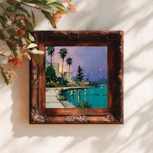 May include: A framed landscape painting depicts a coastal scene at dusk. The artwork features palm trees, buildings, and a body of water with reflections. The frame is ornate, with a dark brown finish. The painting's colors include teal, purple, and yellow.