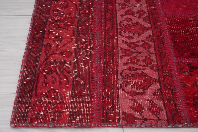 K&ouml;nnte beinhalten: Ein roter und rosafarbener Vintage-Teppich mit einem floralen Muster. Der Teppich hat einen Fransenrand und ist aus Wolle.